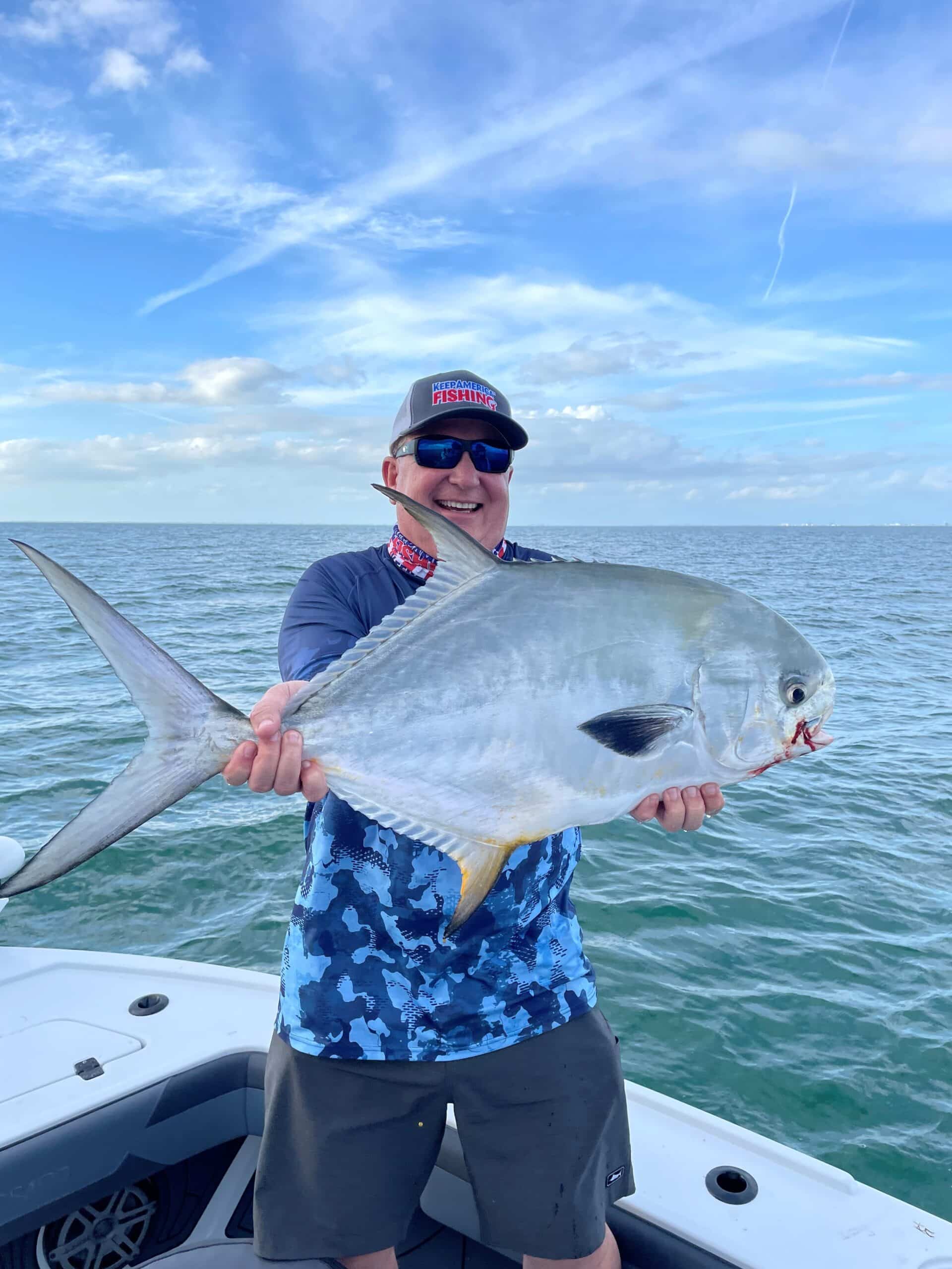 A person on a boat holding a large fish with the ocean in the background. Vote yes on Amendment 2.