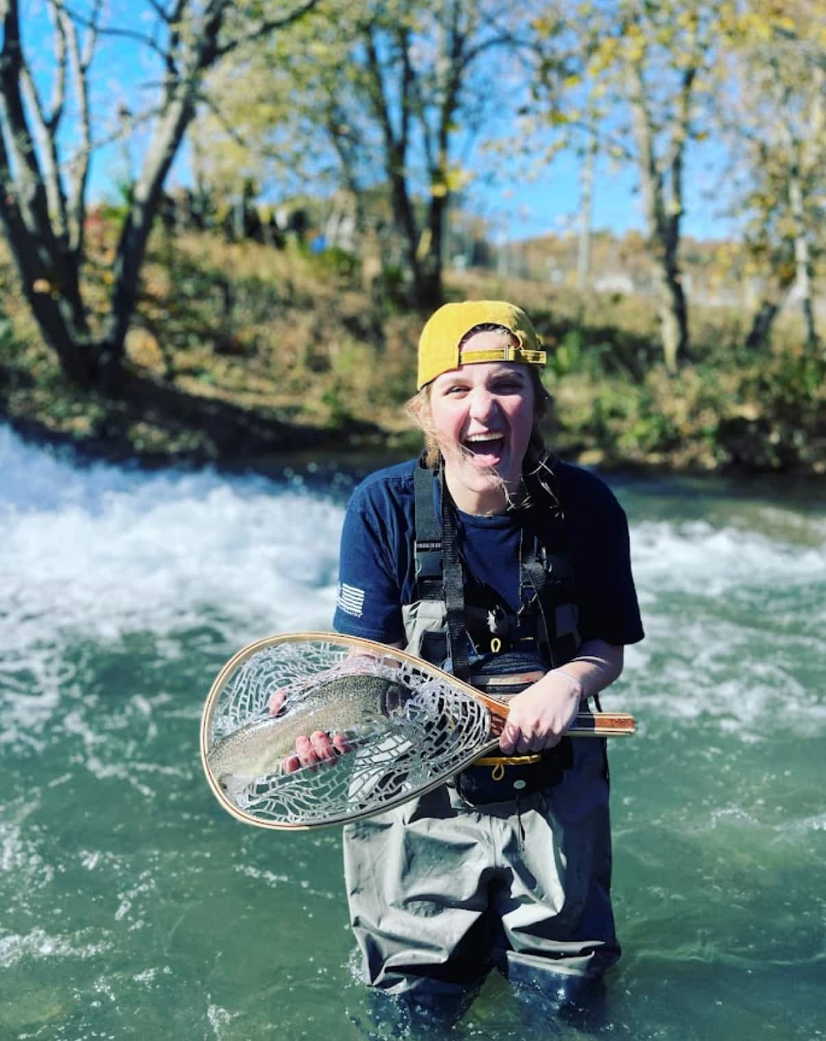 happy woman caught fish and is holding it in a net-vert